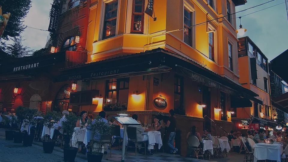 Sarı cepheli köşe bina ve İncili Mozaik’in sokak masaları
